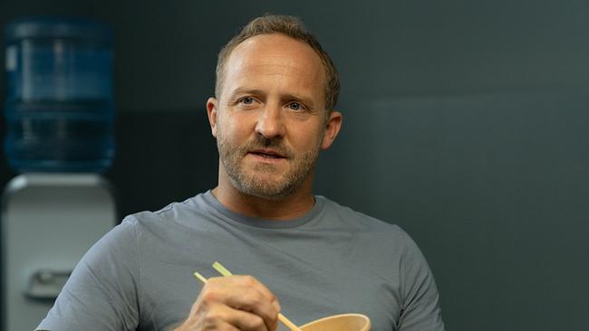 Maximilian Brückner als Kommissar Max Steiner sitzt in einem Innenraum und isst aus einem Becher mit Essstäbchen.