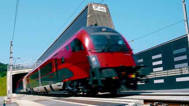 Ein roter Schnellzug fährt mit hoher Geschwindigkeit aus einem Tunnel ins Freie.