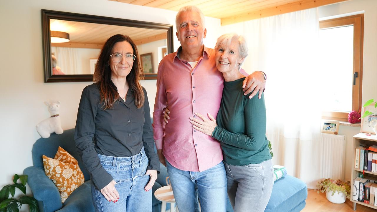 Nina Horowitz mit Sieglinde und Christian, die sich umarmen, stehen in einem hellen Wohnzimmer.