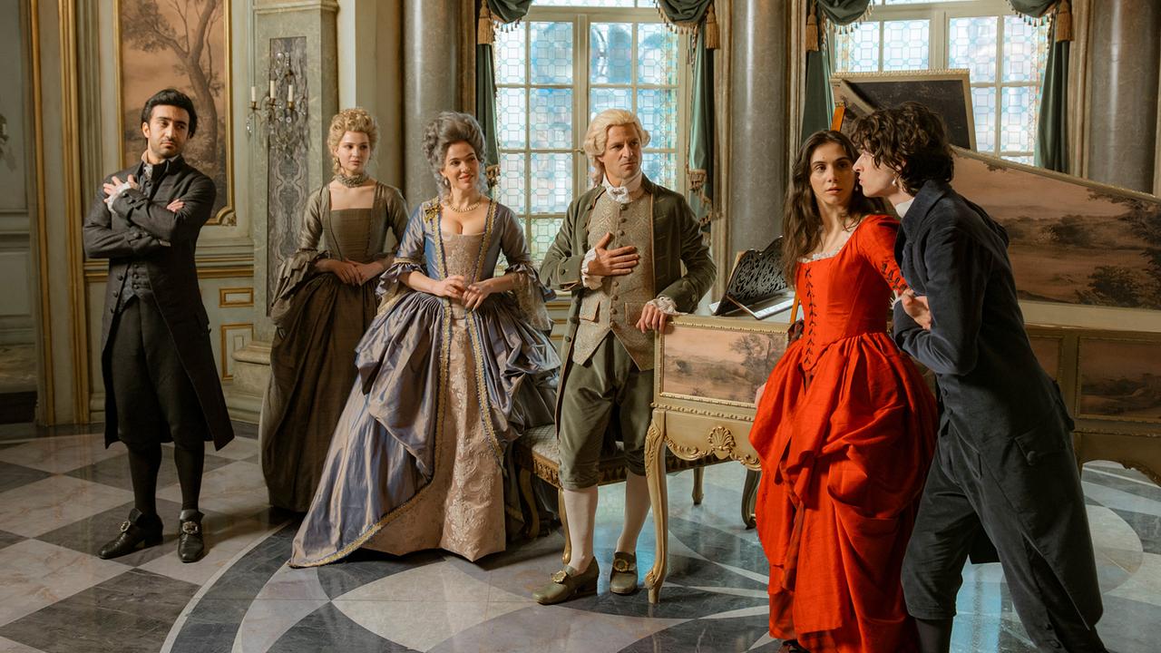 © ORF/ARD/Story House Pictures GmbH/Armands Virbulis Eidin Jalali, Lisa Vicari, Verena Altenberger, Philipp Hochmair, Havana Joy und Eren M. Güvercin in prachtvollen barocken Kostümen posieren in einem prunkvollen Saal neben einem Cembalo.