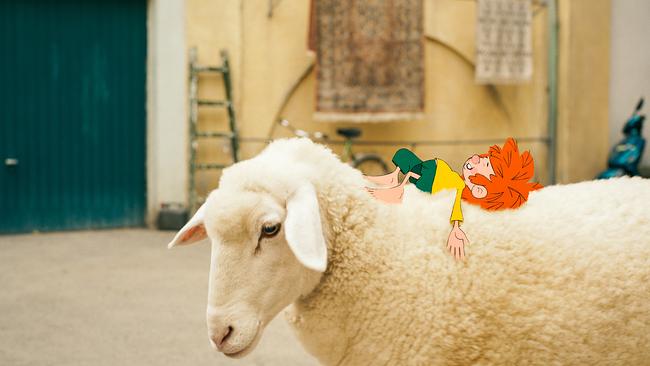 © ORF/Beta Film/NEUESUPER GmbH/RTL Pumuckl, eine gezeichnete rothaarige Kinderfigur, liegt auf dem Rücken eines weißen Schafes in einem Hof.