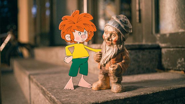 © ORF/Beta Film/NEUESUPER GmbH/RTL Pumuckl, eine gezeichnete rothaarige Kinderfigur, steht abends neben einem aus Holz geschnitzten Heinzelmännchen auf einer kleinen Stufe vor einem Hauseingang und berührt es mit einer Hand.