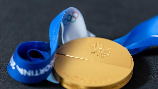 Eine goldene olympische Medaille mit blauem Band und dem Logo der Olympischen Ringe in Nahaufnahme bei den Olympischen Winterspielen Milano Cortina 2026.