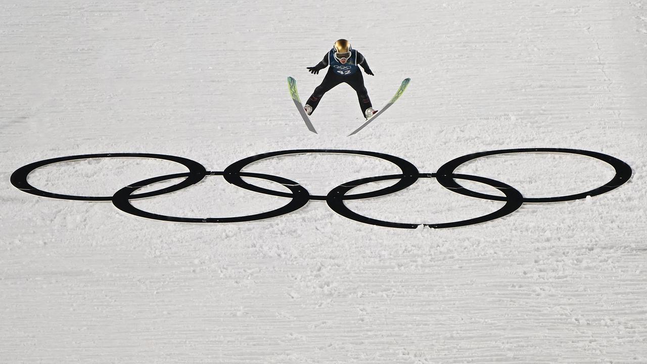 © APA/AFP/Javier SORIANO Skispringer Stephan Embacher springt während des Trainings auf der Normalschanze, unter ihm sind die großen olympischen Ringe zu sehen - bei den Olympischen Winterspielen Mailand-Cortina 2026 im Skisprungstadion Predazzo in Predazzo (Val di Fiemme) am 5. Februar 2026.