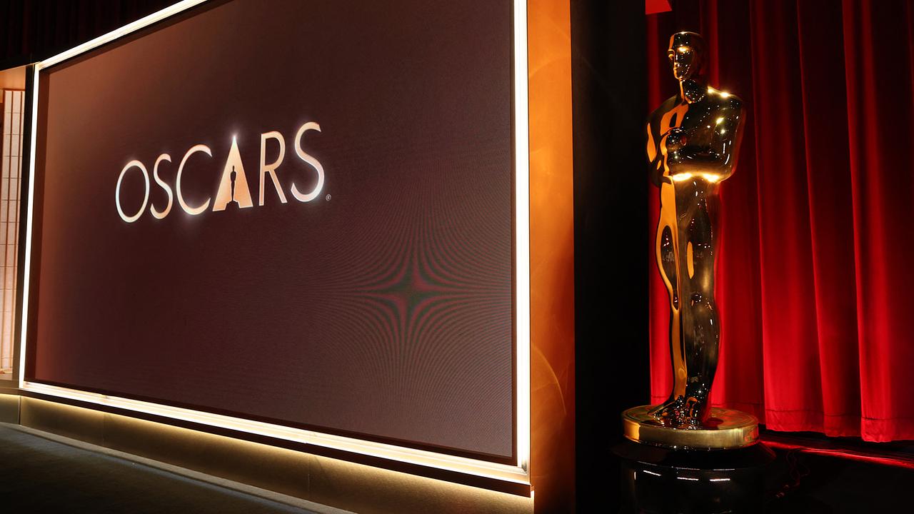 © APA/AFP/VALERIE MACON Eine Bühne mit einer großen „Oscars“-Aufschrift auf einem Bildschirm und einer goldenen Oscar-Statue daneben vor roten Vorhängen