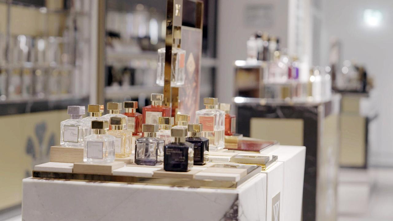 © ORF/Red Monster Film Parfumflaschen in verschiedenen Flakons in unterschiedlichen Farben und Formen auf einem stilvollen Präsentationstisch.