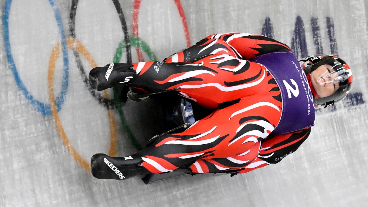 © APA/HANS KLAUS TECHT Die österreichischen Rodlerinnen Selina Egle und Lara Kipp im rot-schwarzen Rennanzug rasen bäuchlings durch den Eiskanal, im Hintergrund sind die Olympischen Ringe zu sehen - beim 3. Training für den Frauen Doppelsitzer-Bewerb im Sliding Center in Cortina d'Ampezzo