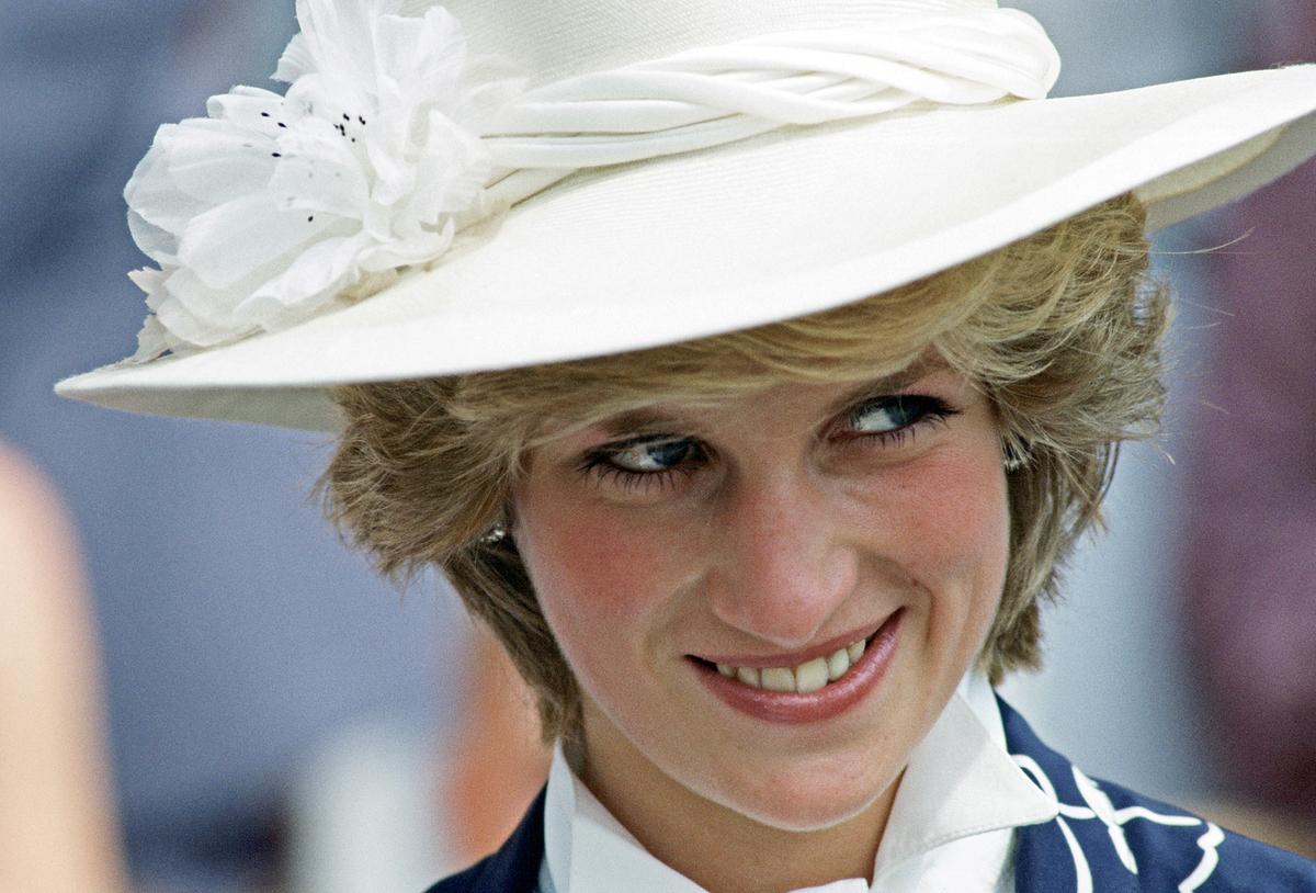 Rivalen: Lady Diana und Elisabeth II.; Im Bild: Prinzessin Diana mit einem großen weißen Hut; lächelt.