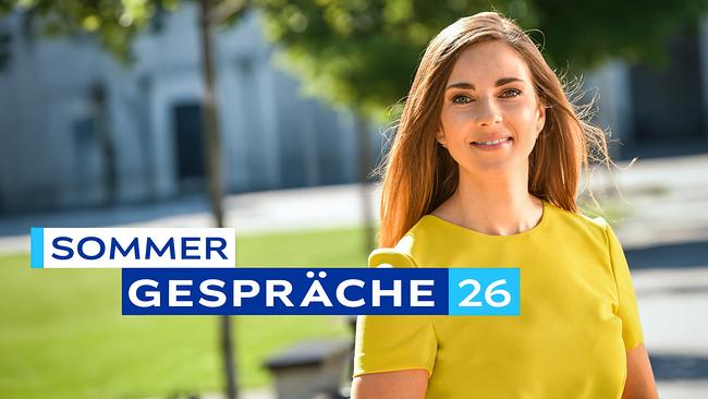 Simone Stribl in gelbem Kleid steht im Freien, vor unscharfem Grün, mit der eingeblendeten Aufschrift „Sommergespräche 26“.