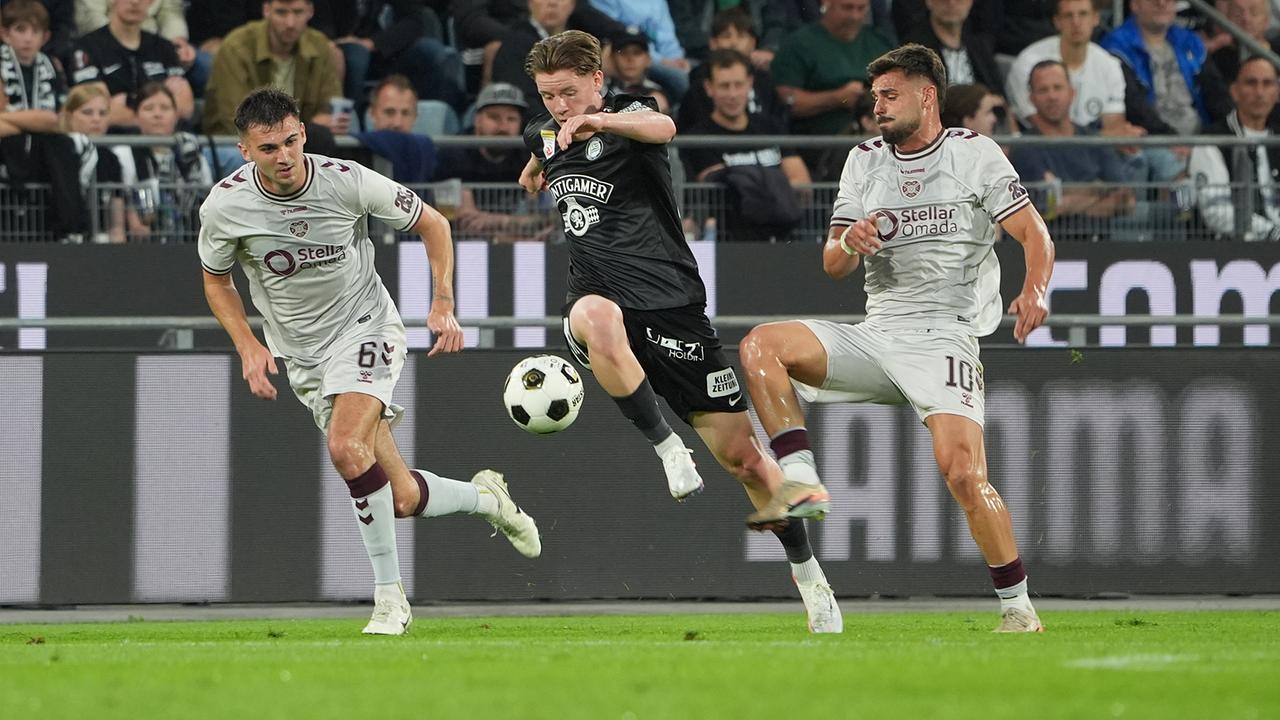 Oisin McEntee (Hearts), Luca Weinhandl (Sturm) und Claudio Braga (Hearts) im Dreikampf um den Fußball während der UEFA-Champions-League Qualifikation zwischen Sturm Graz und Heart of Midlothian in Graz.