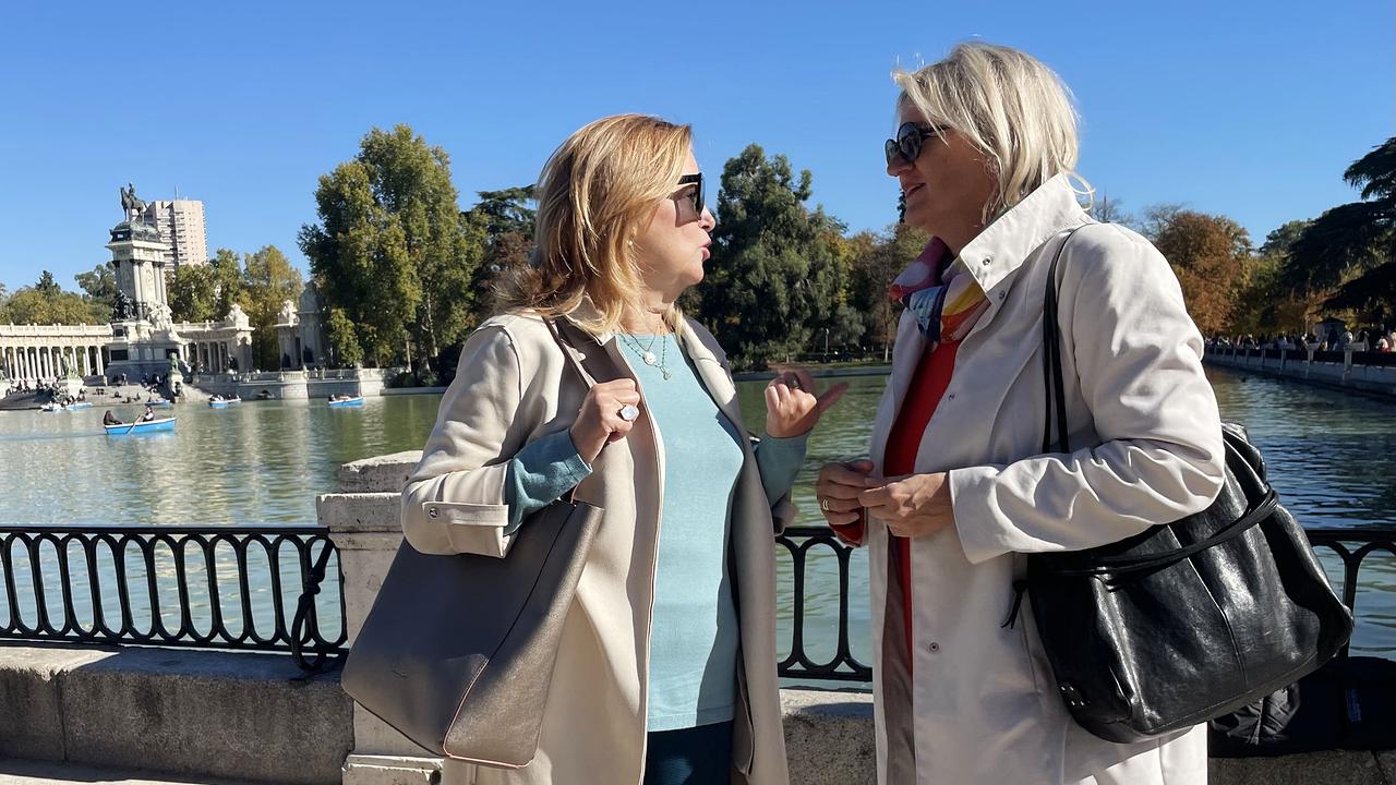 Marta Anguita, links im Bild, im Gespräch mit WELTjournal Reporterin Ines Pedoth an einem sonnigen Tag vor einem Gewässer mit Ruderbooten und einem monumentalen Bauwerk im Hintergrund.