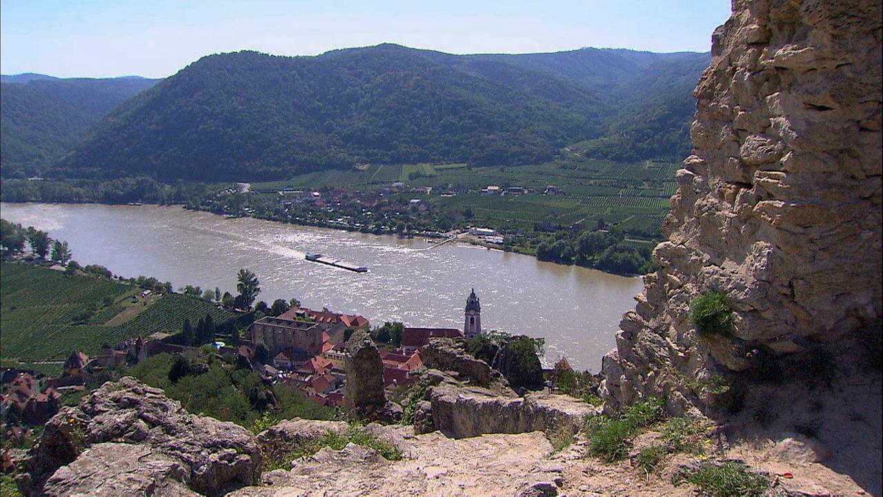 © ORF/Power of Earth/Kurt Mündl Der Blick auf die Donau von der Burgruine Dürnstein hinunter. Der blaue Turm des barocken Stifts ist erkennbar, auf dem Fluss fährt ein Schiff.