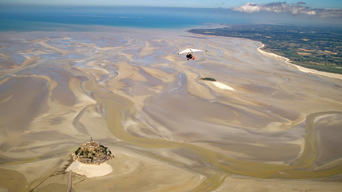 © ORF/Doclights/NDR Naturfilm/Le Cinquieme Reve Die Insel mit der Benediktiner-Abtei Mont Saint-Michel. Es herrscht Ebbe, das Wasser hat sich zurückgezogen und Schlick- und Sandflächen freigelegt.