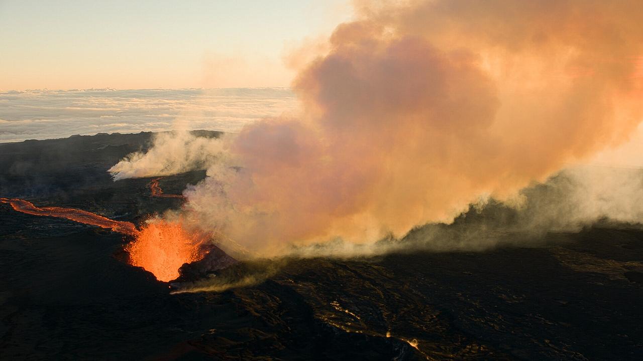 Ein dunkler Berg, glühende, orange Lava wird hochgeschleudert, eine riesige Rauchsäule steigt auf.