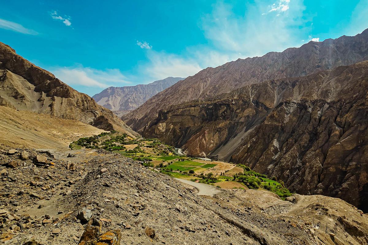 Eine kahle, felsige Schlucht, am Grund fließt ein Fluß zwischen grünen Feldern.