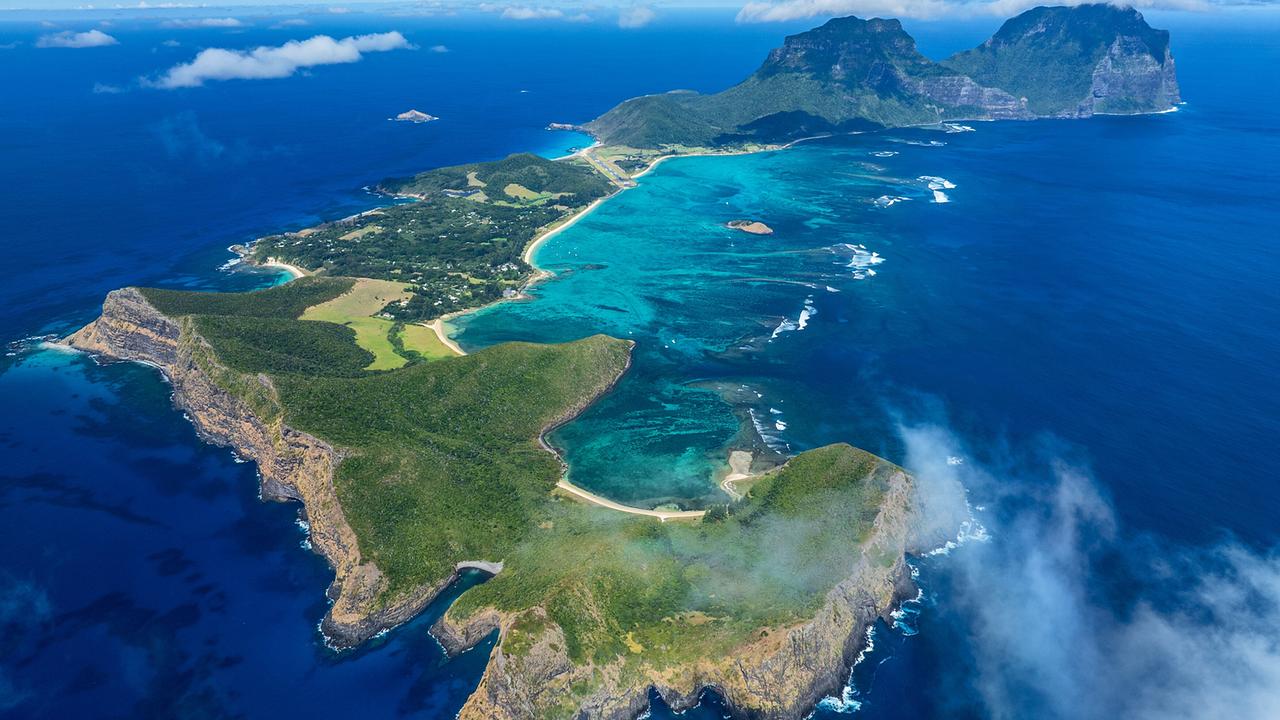 Eine Insel mit zwei Bergen im Norden mitten im Ozean. Ein feines Band von Sandstränden umrahmt den flachen westlichen Teil. Steile Klippen befinden sich im Süden.