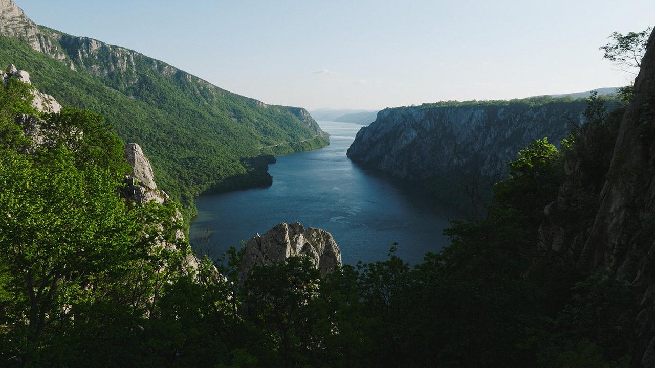 Die Donau fließt zwischen zwei steilen, grün bewachsenen Felswänden ins offene Meer.